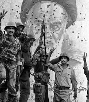 Iraanse soldaten voor een portret van Khomeini, dat door kogels is doorzeefd